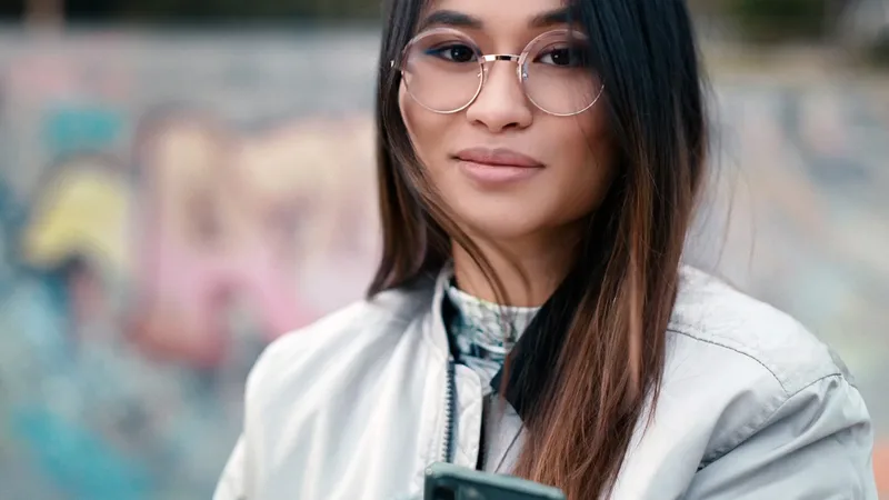ZEISS Single Vision SmartLife Individual Lenses, ZEISS SmartLife photo of a wearer in round spectacles holding a smartphone outdoors
